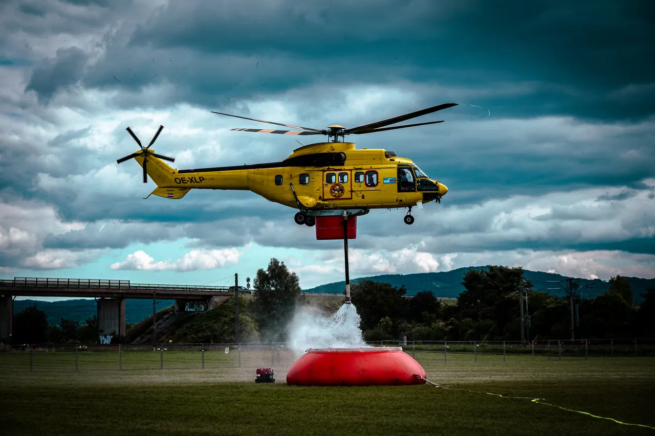 Hubschrauber mit Löschwasserbehälter über einem Faltbecken