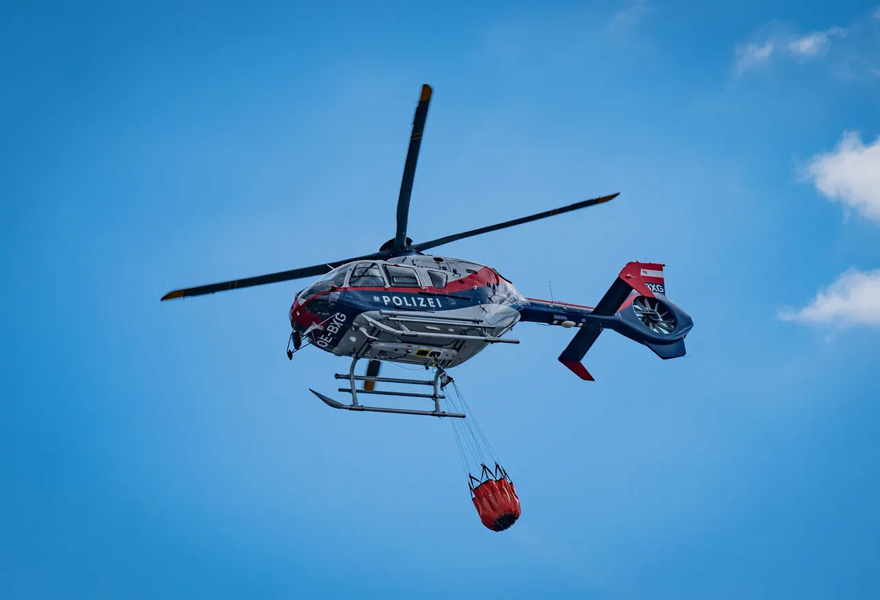 Hubschrauber mit Außenlastbehälter vor blauem Himmel